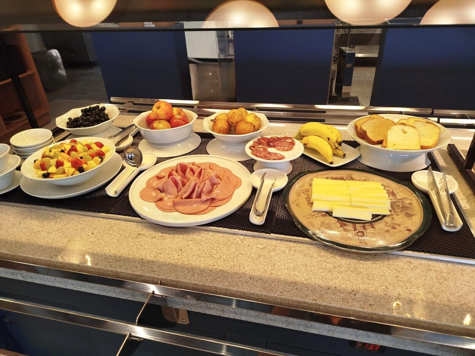 A buffet with various food items including fruits, meats, and cheese.