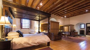 Un dormitorio tradicional con cama con dosel, vigas de madera en el techo y un tapete rojo estampado.