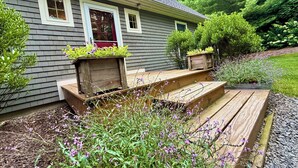 A house with a front porch, wooden steps, and flower planters.