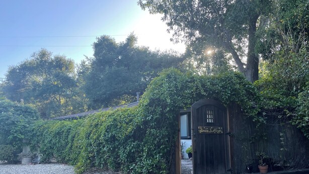 A rustic wooden cottage with a gravel driveway and a sign reading "Deini Cottage." - Charming guest cottage in Santa Barbara with access to hiking and the  beach (Santa Barbara)