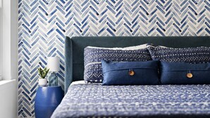 A bedroom with a patterned wallpaper, a blue bedspread, and matching pillows. - MCM Condo Near DT SoCo Pet Friendly (Austin)