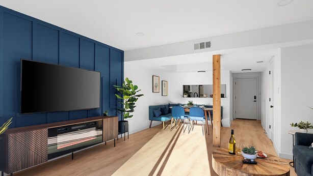 A modern living room with a flat-screen TV, a wooden entertainment unit, a blue sofa, a dining area with a wooden table, and a kitchen in the background. - MCM Condo Near DT SoCo Pet Friendly (Austin)