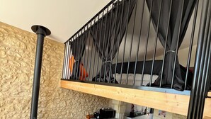 Una cocina moderna con pared de piedra, estufa negra y mesa de comedor de madera.