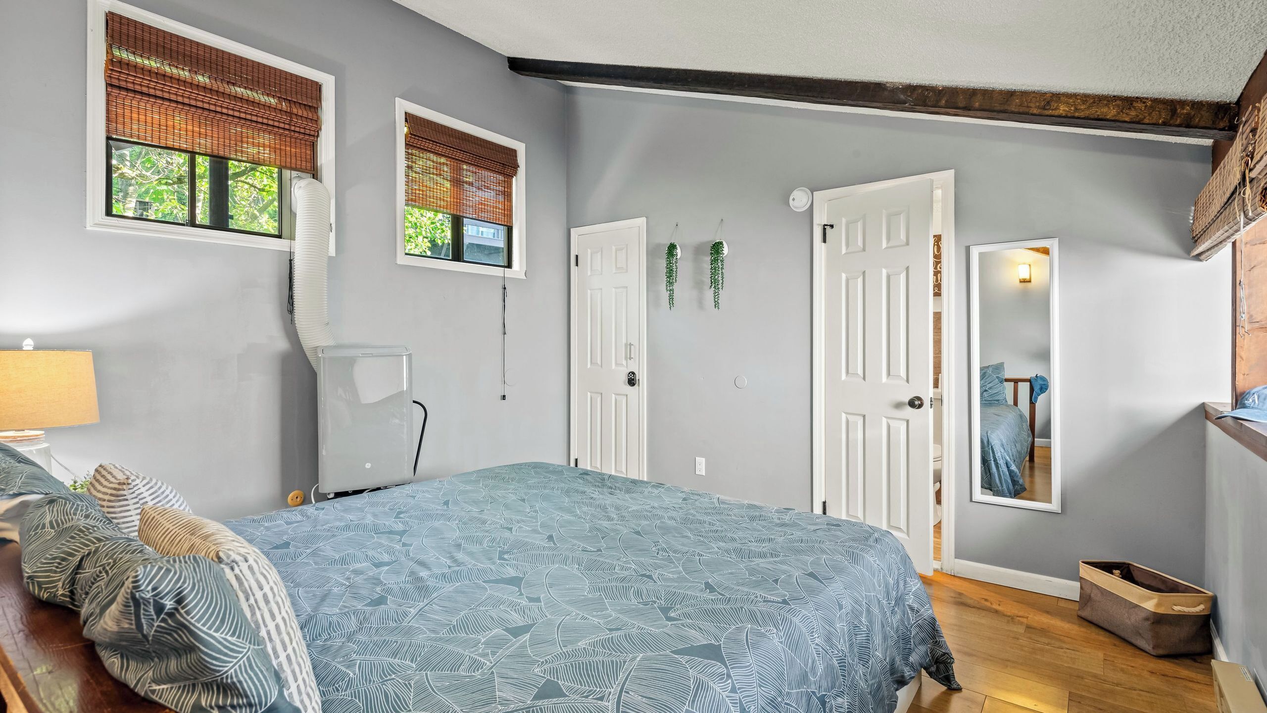 A bedroom with a bed, a radiator, a door, and a window with blinds.