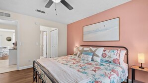 A bedroom with a bed, a ceiling fan, a nightstand, and a painting on the wall. - Private Heated Pool | Lanai + Fire Pit (Largo)
