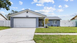 A single-story house with a garage, a small front yard, and a clear sky. - Private Heated Pool | Lanai + Fire Pit (Largo)