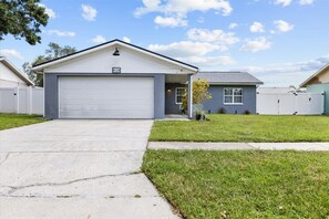 A single-story house with a garage, a small front yard, and a clear sky.