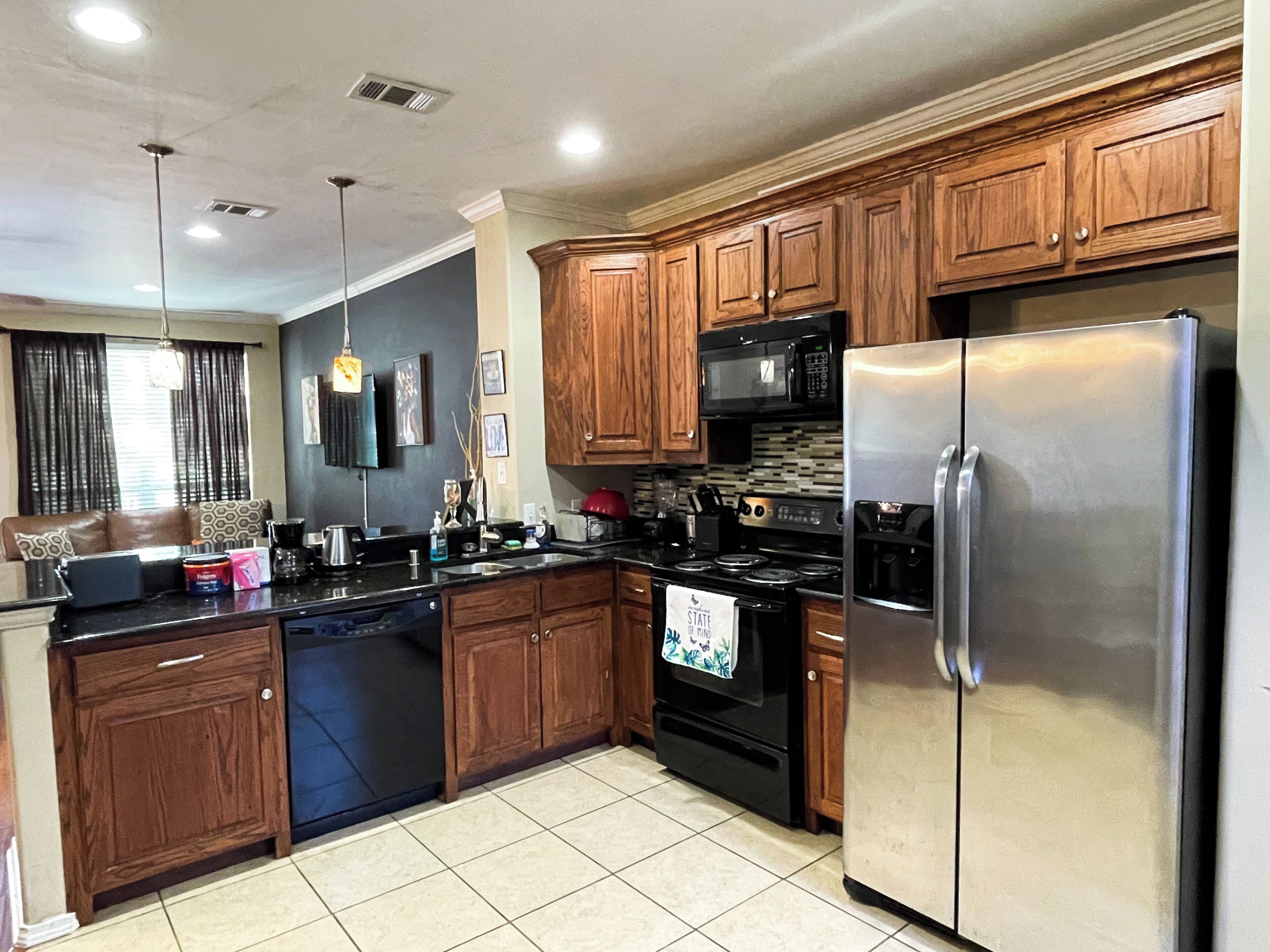 A modern kitchen with wooden cabinets, stainless steel appliances, and a black dishwasher.