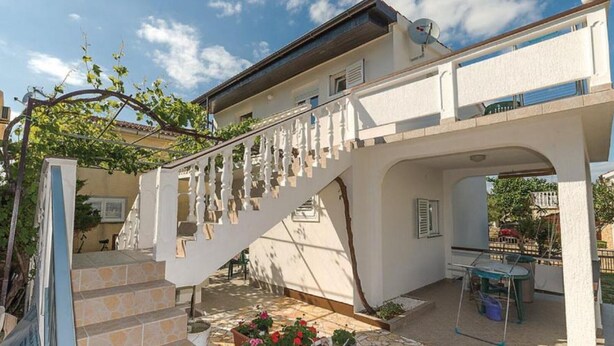 A white building with a staircase leading to a balcony.