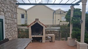 Eine Terrasse im Freien mit einer Steinwand, einem Holztisch und einem Backofen aus Ziegeln.