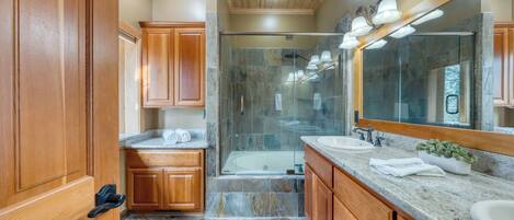 A bathroom with wooden cabinets, a glass-enclosed shower, a bathtub, and a large mirror.