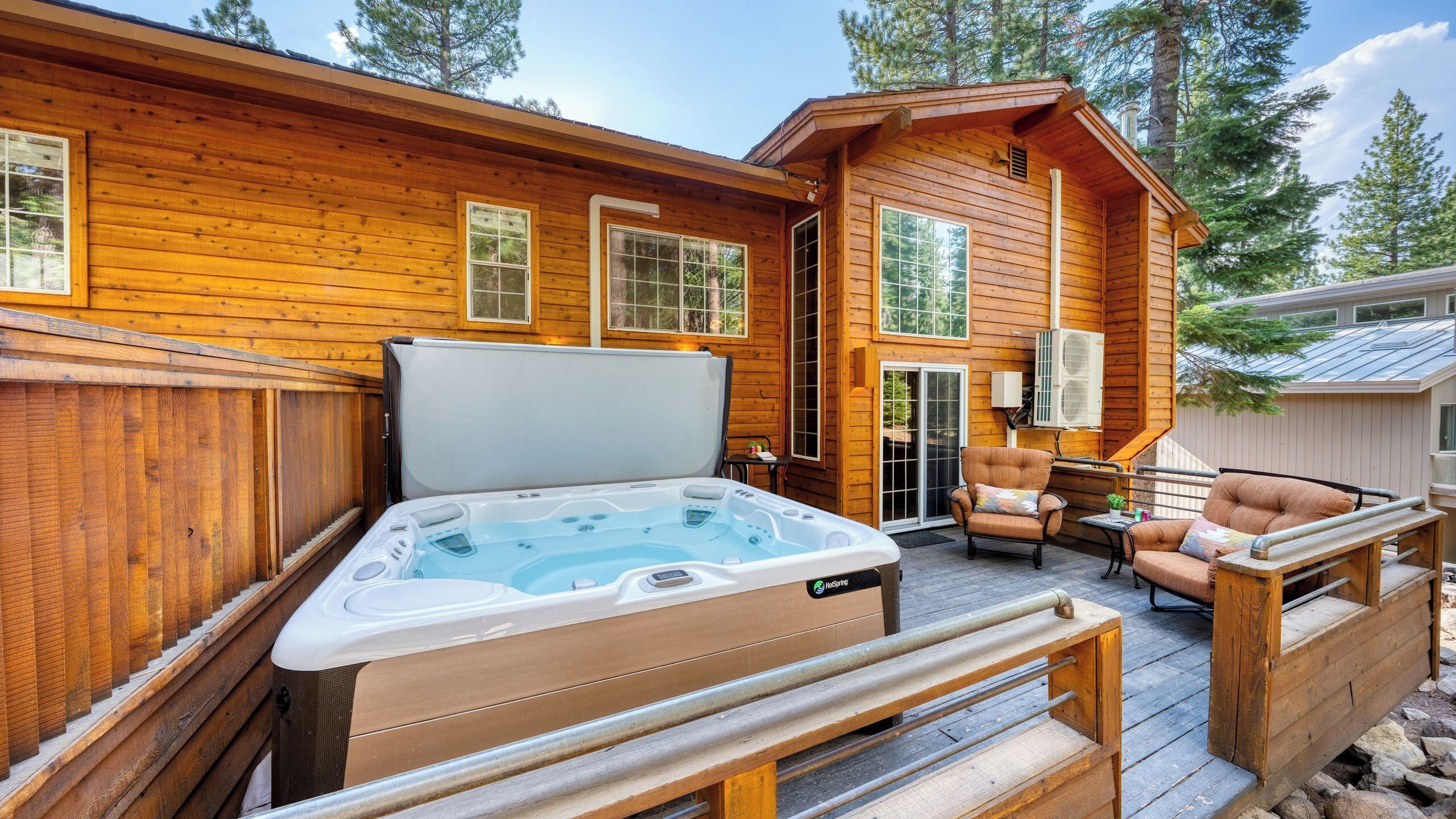 Una cabaña de madera con jacuzzi, mobiliario exterior y una terraza.