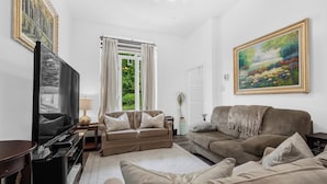 A living room with a sofa, a television, a lamp, and a painting on the wall.