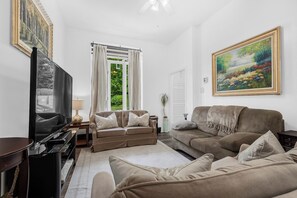Ett vardagsrum med en soffa, en tv, en lampa och en tavla på väggen.