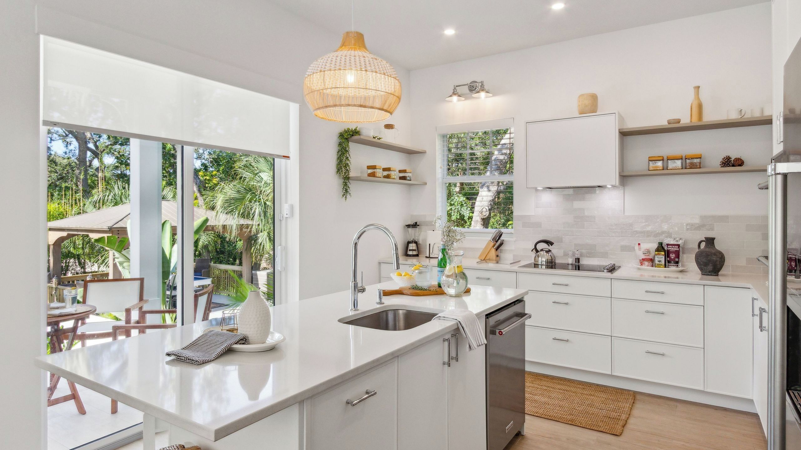 A modern kitchen with white cabinetry, a central island, and a view of the outdoors.