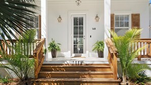 A wooden staircase leading to a white door with a number plate, flanked by potted plants and wooden railings. - Serenity at Surfside by Avantstay Pool, Porches, Fire Pit & Arcade Near Vilano Beach (St. Augustine)