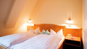 Une chambre avec deux lits, une tête de lit en bois, des lampes de chevet et une petite table avec une lampe.
