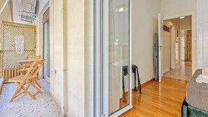 A modern hotel room with a sliding glass door, wooden flooring, a bed with a green headboard, and a small seating area with a table and chairs. - Your Athens Apartment near Acropolis II (Athina)