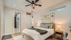 A bedroom with a bed, bedside tables, a ceiling fan, and wall decorations.