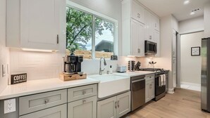 A modern kitchen with white cabinetry, a coffee maker, a toaster, and a stainless steel refrigerator.