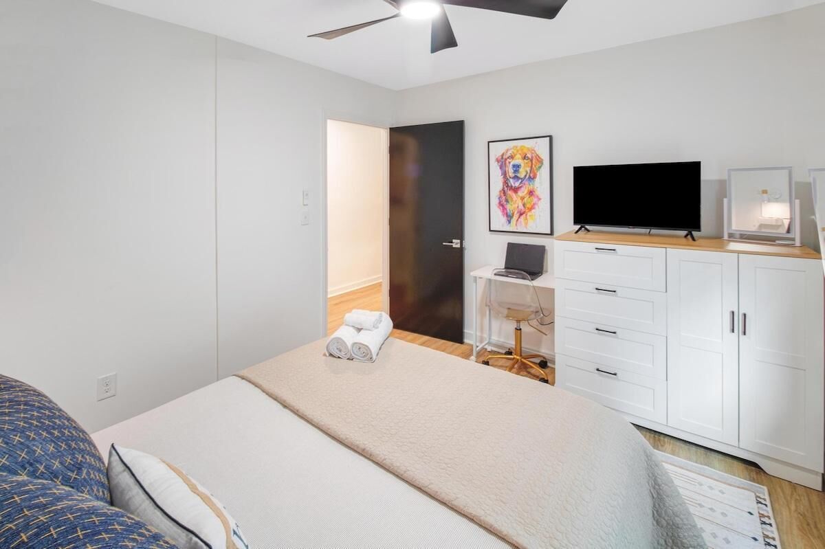 Ein modernes Hotelzimmer mit einem Bett, einem Schreibtisch, einem Fernseher und einer Tür zu einem weiteren Raum.