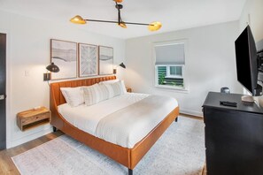 Ein Schlafzimmer mit einem Bett, Nachttischen, einem Fernseher und Bildern an der Wand.