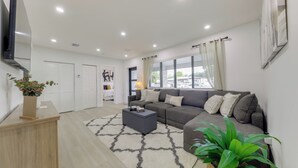 A modern living room with a grey sectional sofa, a coffee table, a wooden cabinet, and a potted plant. - 3 Mi to Hard Rock Stadium: Retreat w/ Private Yard (Miramar)