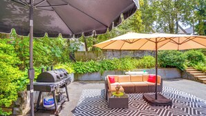 Een terras met een barbecue, tuinmeubilair en parasols.