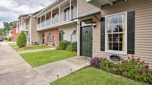 A row of townhouses with a front porch, a green door, and a small garden with flowers.