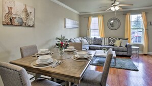 A dining area with a wooden table set for four, a gray sofa, and a ceiling fan.