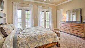 A bedroom with a bed, dresser, mirror, and ceiling fan.