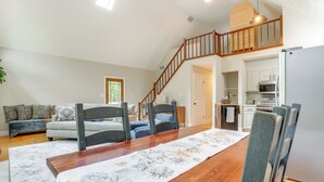 A spacious living area with a dining table, chairs, a sofa, and a staircase leading to a kitchen. - Pet-Friendly Lake Monticello Home w/ Perks! (Palmyra)