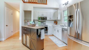 A modern kitchen with white cabinets, stainless steel appliances, and a wooden island. - Pet-Friendly Lake Monticello Home w/ Perks! (Palmyra)