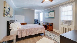 Ein Schlafzimmer mit Bett, Deckenventilator, Heizkörper und einem Fenster mit Jalousien.