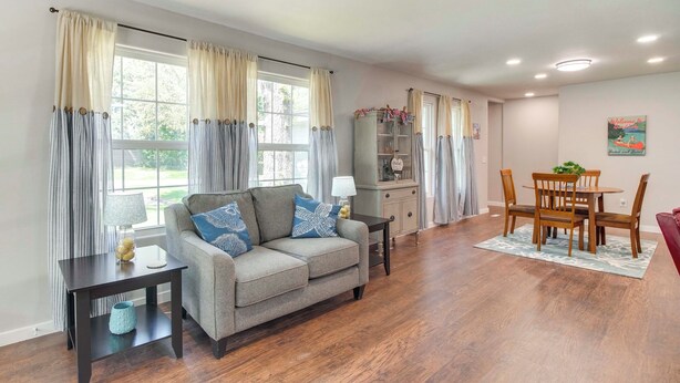 A living room with a sofa, a coffee table, and a dining area with a table and chairs. - Walk to Marina & Lake: Family Retreat in Afton! (Afton)