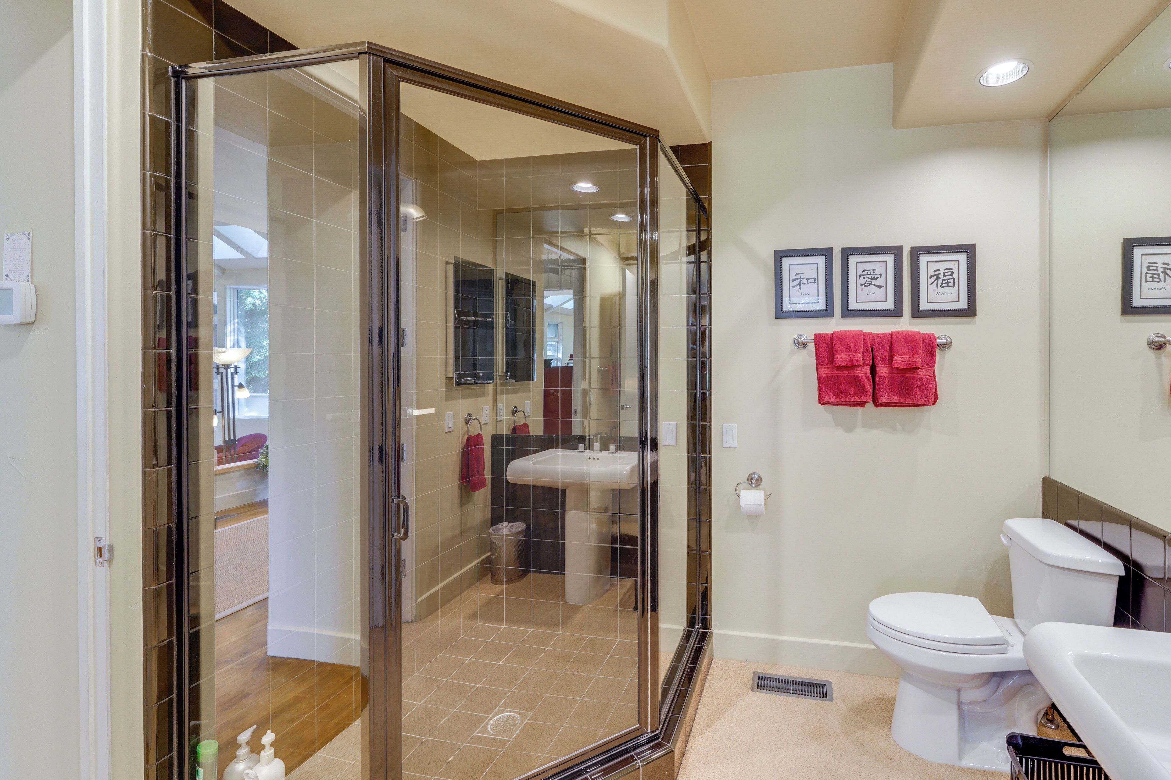 Een moderne badkamer met een douchecabine van glas, een wit toilet en een wastafel.