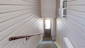 A narrow stairway with a metal handrail, a white door at the top, and an air conditioning unit mounted on the wall. - Near Loudoun Wine Trail: Apt w/ Restaurant On-Site (Hamilton)
