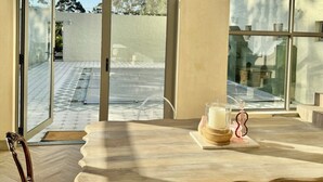 A room with a large window, a wooden table, and a chair. - Grande Casa (Stellenbosch)