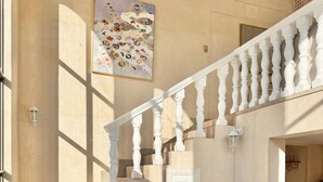A staircase with a white balustrade leading to a landing. A wooden desk with drawers and a chair is positioned near the staircase. - Grande Casa (Stellenbosch)