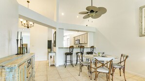 A spacious kitchen with a dining area, featuring a central island, bar stools, and a ceiling fan. - Screened Lanai + Workspace! Naples Stay Near Gulf (Naples)