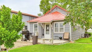 Ein eingeschossiges Haus mit rotem Dach, einer Veranda und einer kleinen Terrasse.
