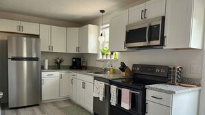 Une cuisine moderne dotée d’appareils électroménagers en acier inoxydable, de meubles blancs et de plans de travail en granit.