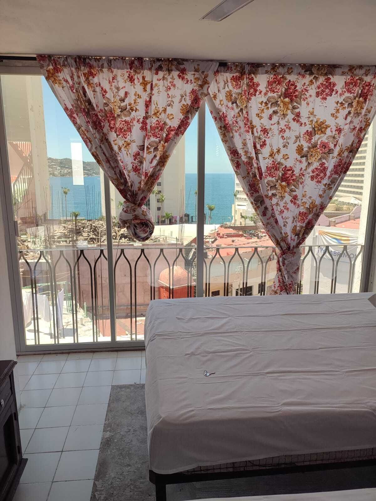 Un dormitorio con cama, vista al mar y balcón con barandilla.