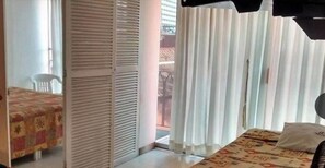 A hotel room with a bed, a chair, and a sliding door leading to a balcony. - Condesa Americana Acapulco (Acapulco)