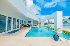 Ein modernes Haus mit Pool, Sitzgelegenheit im Freien und Meerblick.