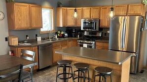 Una cocina moderna con armarios de madera, electrodomésticos de acero inoxidable y una isla central con taburetes de bar.