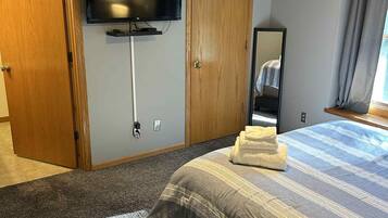 Une chambre d’hôtel avec un lit, un ventilateur de plafond, une télévision et un miroir.