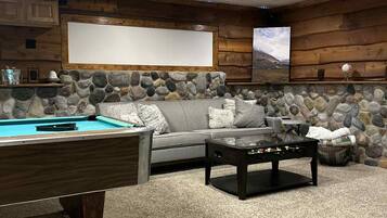 A cozy indoor space with a pool table, a sofa, and a stone wall.