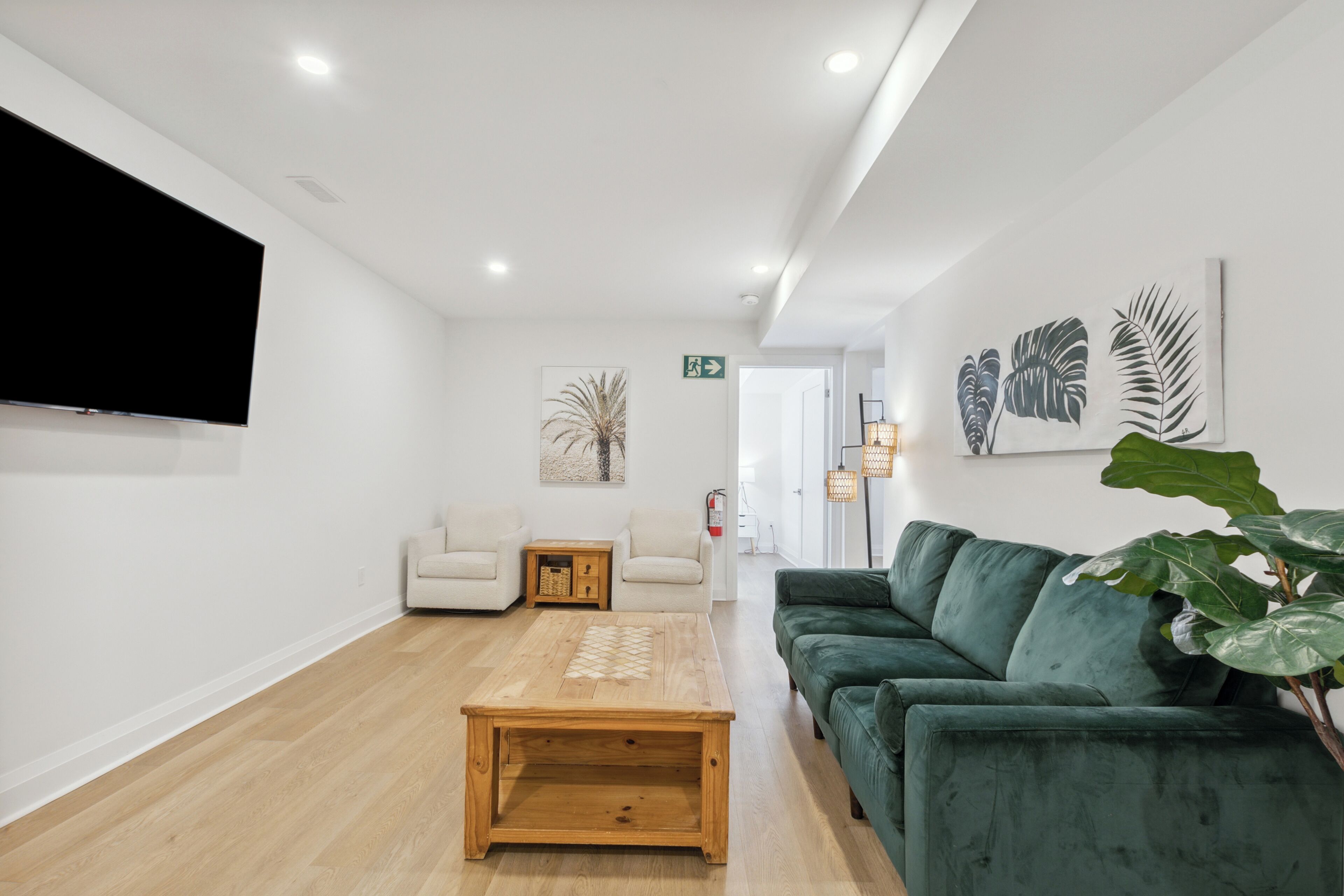 Un salon moderne avec une table basse en bois, un canapé vert et un téléviseur à écran plat fixé au mur.