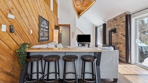Una cucina moderna con una parete in legno a contrasto, un angolo bar con sgabelli e un'ampia finestra che offre vista all'esterno.